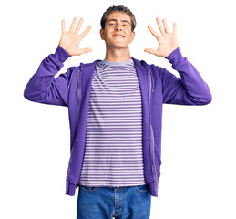 Young handsome man wearing casual purple sweatshirt showing and pointing up with fingers number ten while smiling confident and happy.