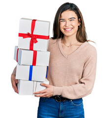 Young caucasian girl holding gifts smiling with a happy and cool smile on face. showing teeth.