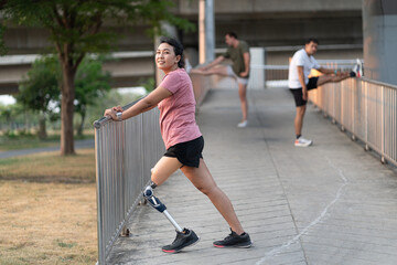 Happy exercise Asia woman with prosthetic leg and friend stretching at  park city	