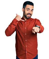 Young hispanic man with beard wearing casual shirt smiling doing talking on the telephone gesture...