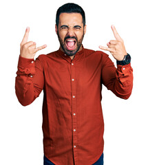 Young hispanic man with beard wearing casual shirt shouting with crazy expression doing rock symbol...