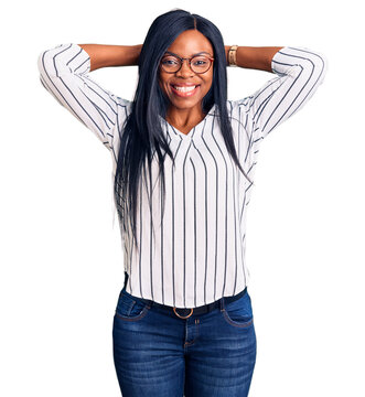 Young african american woman wearing casual clothes and glasses relaxing and stretching, arms and hands behind head and neck smiling happy