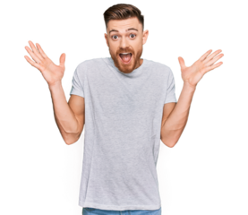 Young redhead man wearing casual grey t shirt celebrating crazy and amazed for success with arms raised and open eyes screaming excited. winner concept