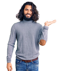 Young arab man wearing casual clothes smiling cheerful presenting and pointing with palm of hand looking at the camera.