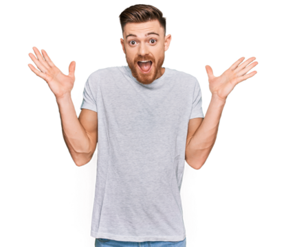 Young redhead man wearing casual grey t shirt celebrating crazy and amazed for success with arms raised and open eyes screaming excited. winner concept