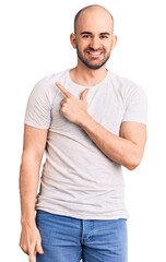 Young handsome man wearing casual t shirt cheerful with a smile of face pointing with hand and finger up to the side with happy and natural expression on face