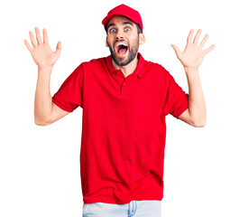 Naklejka premium Young handsome man with beard wearing delivery uniform celebrating crazy and amazed for success with arms raised and open eyes screaming excited. winner concept