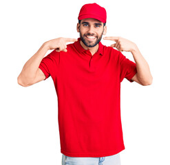 Young handsome man with beard wearing delivery uniform smiling cheerful showing and pointing with fingers teeth and mouth. dental health concept.