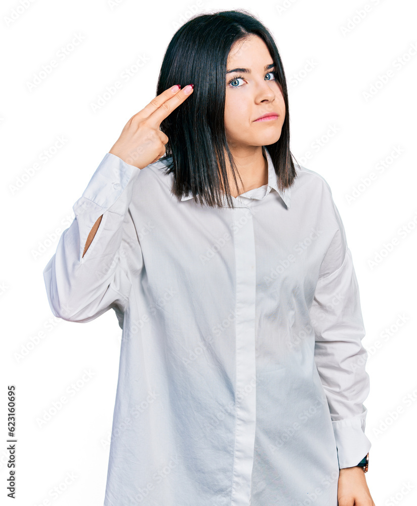 Poster Young brunette woman with blue eyes wearing oversize white shirt shooting and killing oneself pointing hand and fingers to head like gun, suicide gesture.