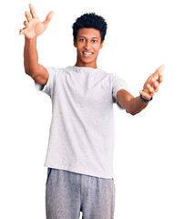 Young african american man wearing casual clothes looking at the camera smiling with open arms for hug. cheerful expression embracing happiness.