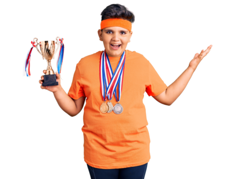 Little boy kid holding champion trophy and wearing medals celebrating victory with happy smile and winner expression with raised hands - Powered by Adobe