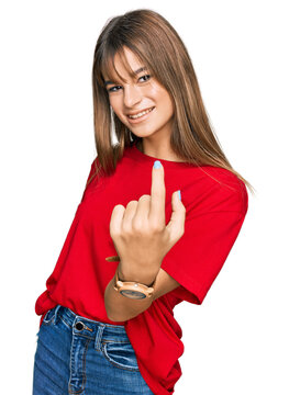 Teenager caucasian girl wearing casual red t shirt beckoning come here gesture with hand inviting welcoming happy and smiling