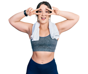 Young hispanic girl wearing sportswear and towel doing peace symbol with fingers over face, smiling cheerful showing victory