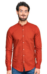 Young hispanic man wearing casual clothes puffing cheeks with funny face. mouth inflated with air, crazy expression.