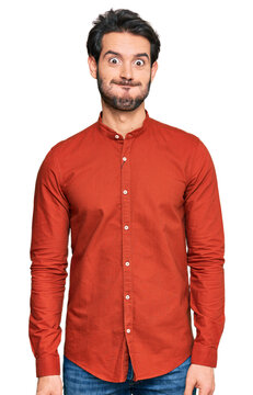 Young hispanic man wearing casual clothes puffing cheeks with funny face. mouth inflated with air, crazy expression.