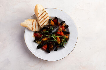 Cooked mussels and toasted bread in a plate.