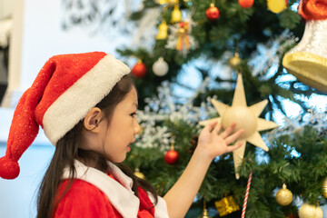 Merry Christmas and Happy Holidays. Girl decorate the Christmas tree indoors.