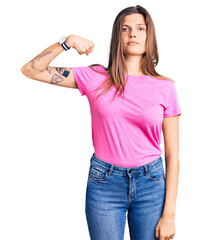 Fototapeta premium Beautiful caucasian woman wearing casual clothes strong person showing arm muscle, confident and proud of power