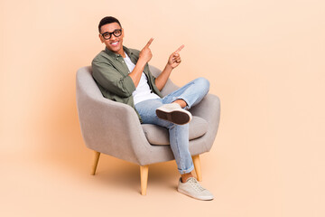 Full size portrait of positive agent man sitting comfort chair indicate fingers empty space...