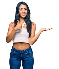Beautiful hispanic woman wearing casual clothes showing palm hand and doing ok gesture with thumbs up, smiling happy and cheerful