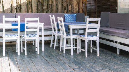 White wood furniture in the kitchen. Wooden furniture on the terrace of the house in summer. Rest in the village. Chairs and tables made of natural wood. Gazebo for sun protection with furniture.