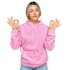 Obraz na płótnie Canvas Young caucasian woman wearing casual sweatshirt relax and smiling with eyes closed doing meditation gesture with fingers. yoga concept.