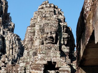 Fototapeta premium Detailed view of stone human faces adorning the towers of the Bayon Temple, a Khmer site in Cambodia.