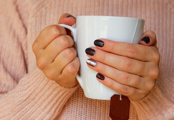 Girl with a sweater holding a cold cup. Concept of cold in Europe in winter 2023