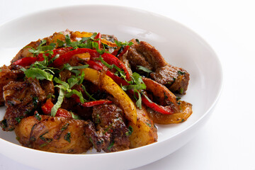 Fried meat with potatoes and vegetables in a plate.