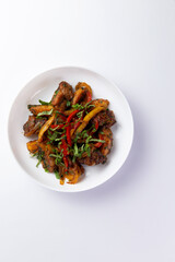 Fried meat with potatoes and vegetables in a plate.