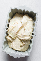 Lemon cake batter in a loaf pan, cake batter about to be baked in a silver baking pan, the process...