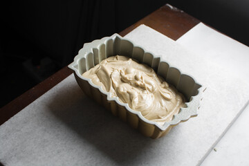 Lemon cake batter in a loaf pan, cake batter about to be baked in a silver baking pan, the process...