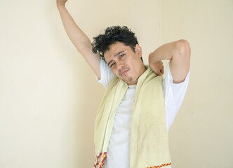 Young man wear white clothes with towel laziness gesture. The photo is suitable to use for daily...