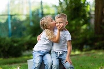 Fototapeta premium Beautiful little girl kissing his friend on natural park background.
