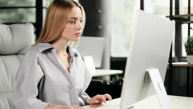 Portrait of busy concentrated blond businesswoman typing browsing checking email in modern workplace Attractive young office worker at the desk and working on the computer indoors