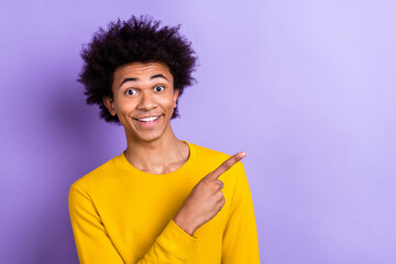 Photo of astonished positive man beaming smile indicate finger empty space information isolated on violet color background