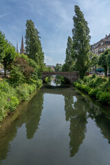 Fototapeta na wymiar Strasbourg, France - 06 26 2023: Strasbourg city: View of a typical bridge reflecting in the river in Vosges Avenue.