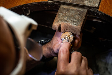 Goldsmith jeweler man working in his crafting jewelry workshop repairing and creating a gold ring...