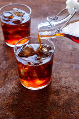 a glass of homemade cold brew coffee with iced on rusty table background.
