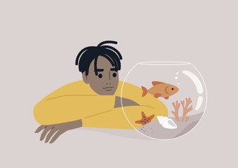 A young African person watching a goldfish swimming in a round water tank
