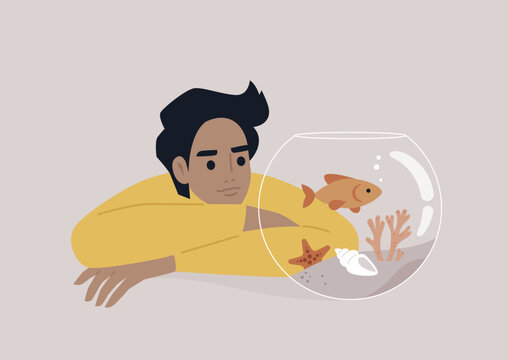 A young Caucasian person watching a goldfish swimming in a round water tank