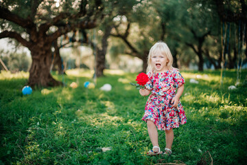 a small child in an elegant bright dress plays in the olive garden