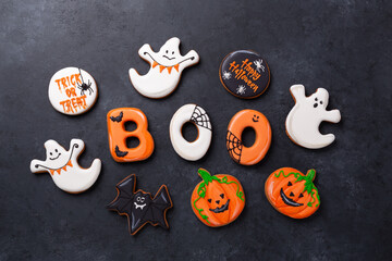 Halloween gingerbread cookies: text BOO, bats, pumpkins and ghosts on dark stone background....