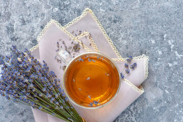 Fresh delicious tea with lavender and bunch of lavender flowers on gray stone table. Top view. Flat lay.