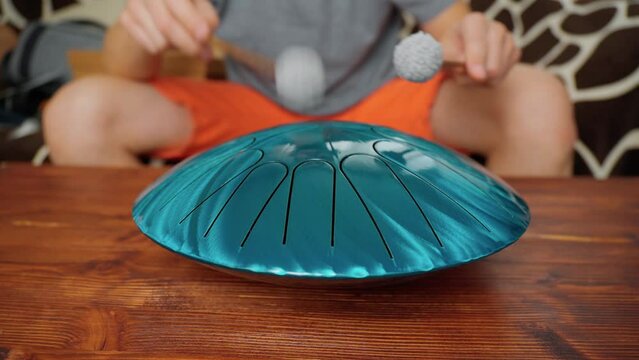 Playing glucophone metal tongue drum relaxing at home. Melody audio tool for meditation, relaxation with deep magical sound.