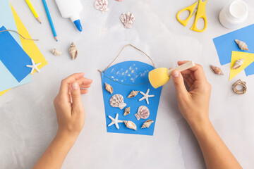 Paper bucket of shells summer idea for kids craft in kindergarten hands ocean's day © Angelina Zinovieva