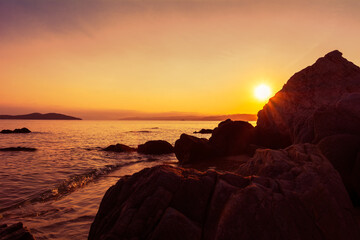 Magical sunset with amazing colors on the sea. Sand, waves and rocks in a beautiful light