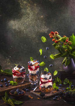 Homemade granola with greek yogurt, berries jam and fresh blackberries and blueberries in glasses