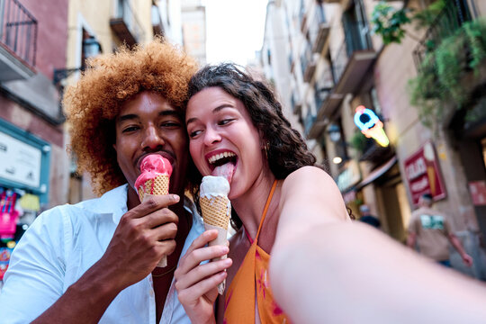 multiethnic couple of tourists taking selfie and eating ice cream - Powered by Adobe