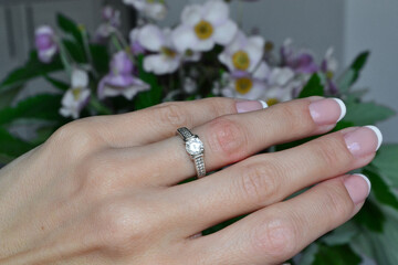 on the background of flowers, the girl shows a ring